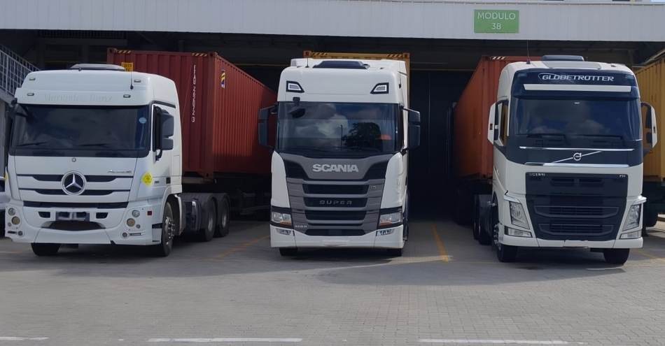 Frota de caminhões da J.A Logística carregando containers no terminal